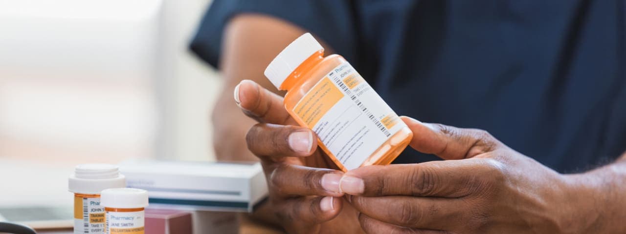 A person's hands holding a prescription medication bottle
